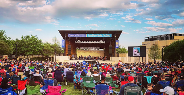 Crowd of people waiting for musical entertainment on stage.