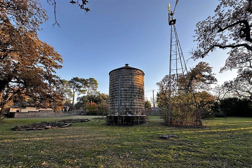 Giant concrete well in the middle of frame next to windmill.