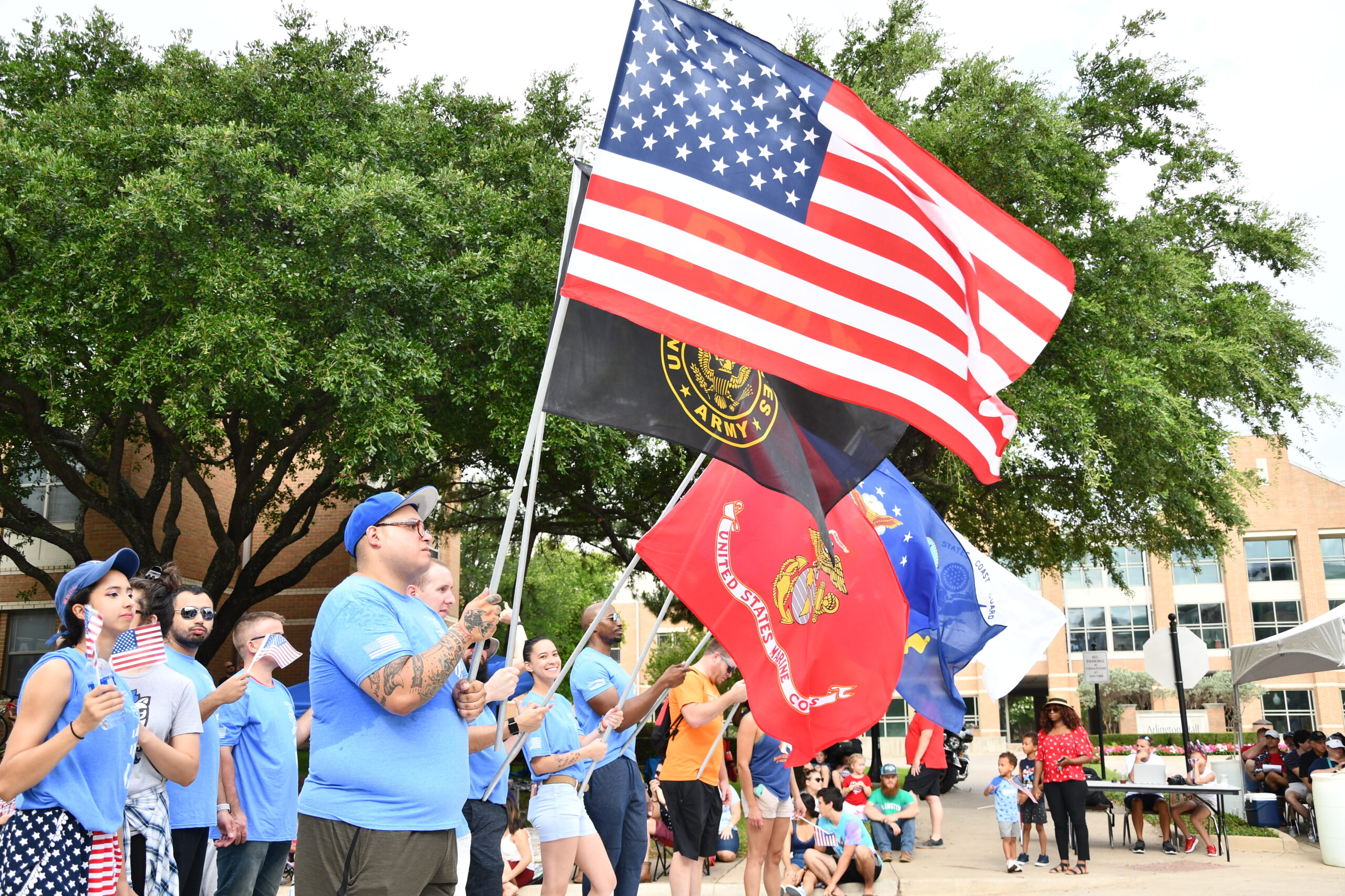 People holding United States of America flags along with flags of the military branches of the nation.