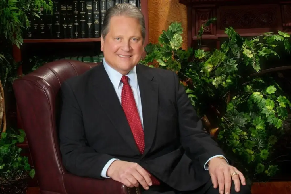 Dr. Robert N. Cluck sits in maroon chair and smiles.