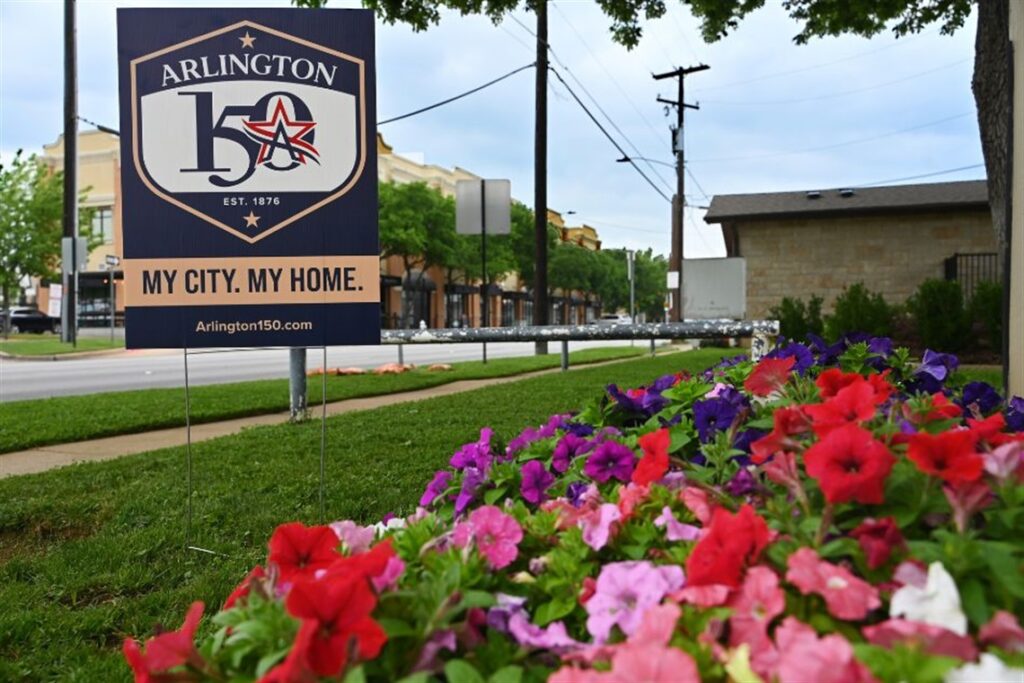 Arlington 150 Anniversary Yard Sign placed in flowerbed in Downtown Arlington.