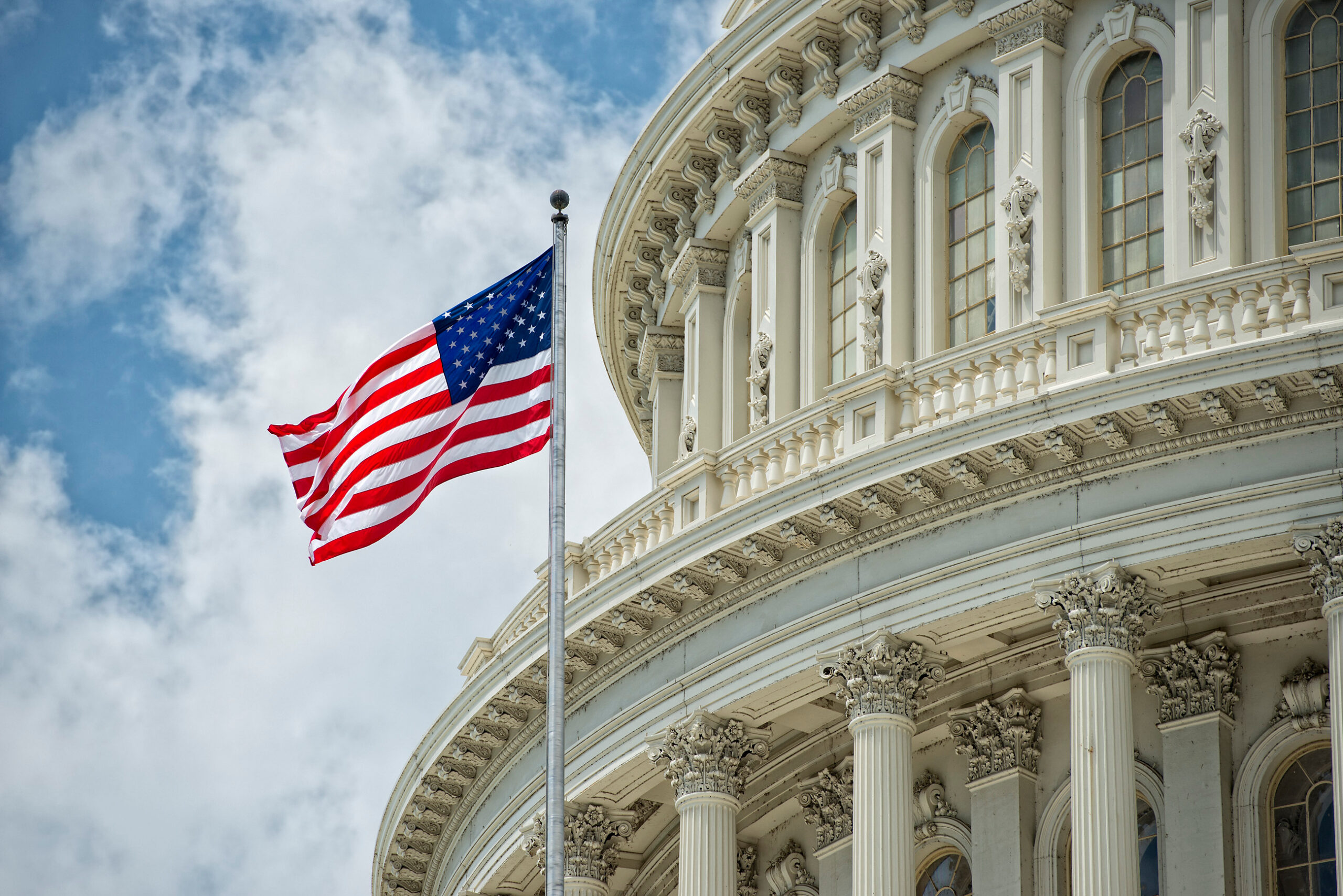 Washington DC Capitol dome detail with waving American flag.