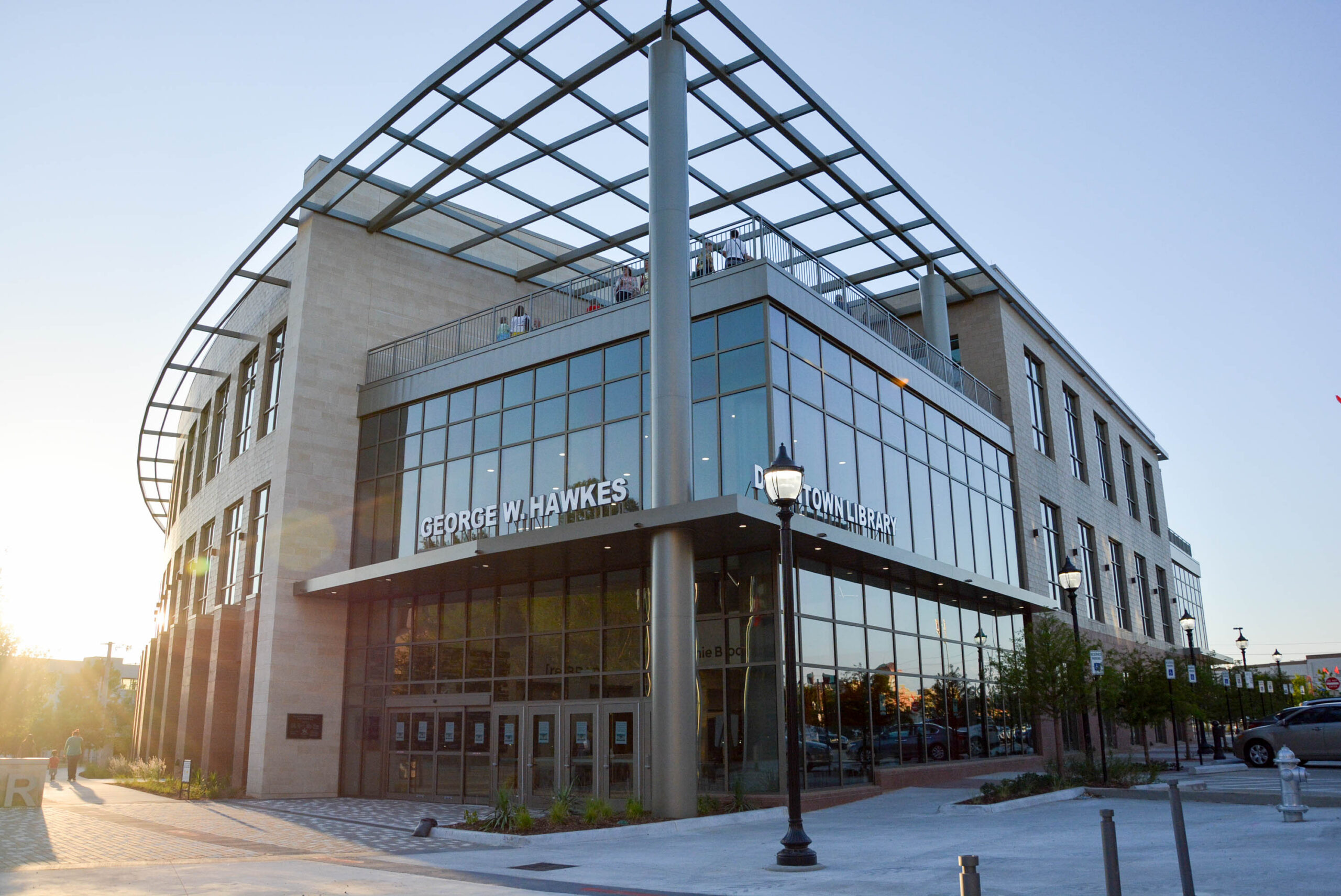 Sun setting behind an entrance to the George W. Hawkes Downtown Library.