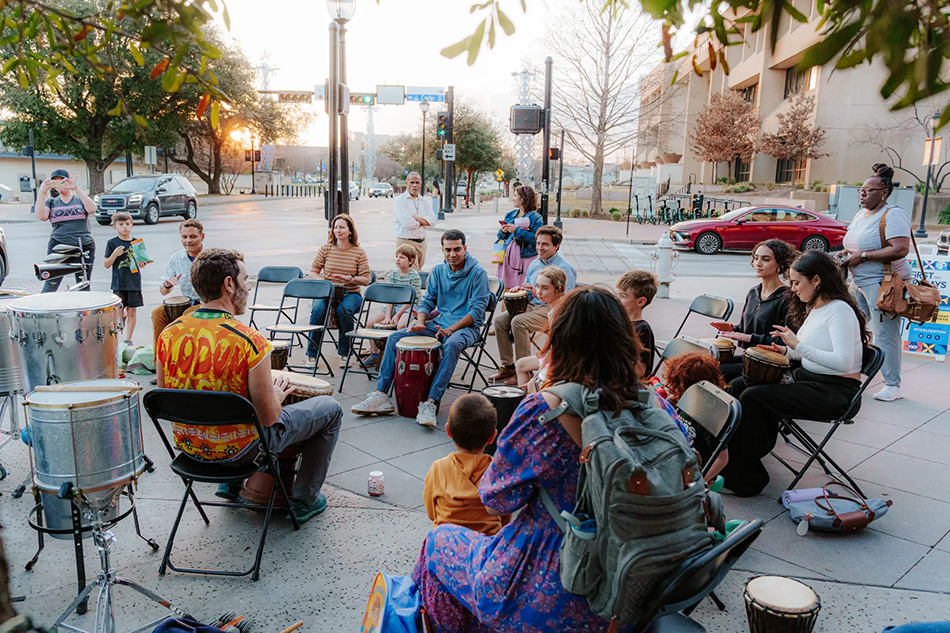 People playing percussion instruments on the sidewalk in Downtown Arlington.