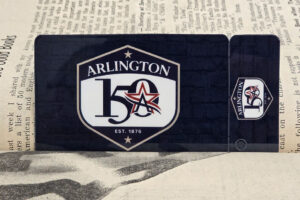A special edition Arlington Library Card with the City of Arlington's sesquicentennial badge in a book.
