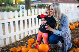 Mom with daughter and pumpkins nearby.