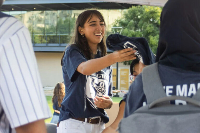 A woman handing out t-shirts.