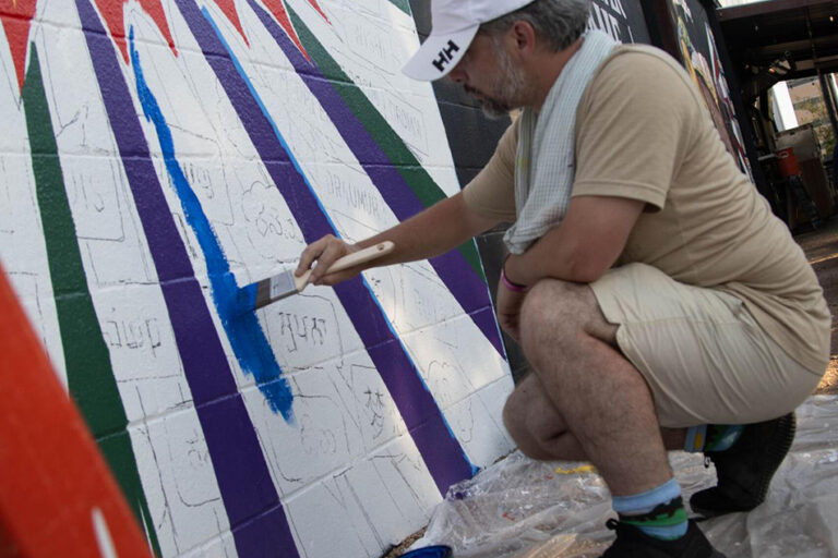 Muralist kneeling to paint.