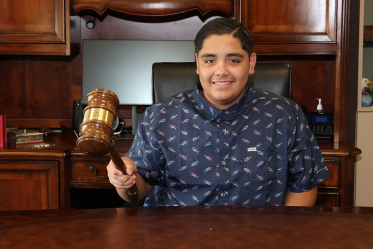 Honorary Mayor for the Day, Aaron Diaz, holds gavel and smiles for a photo.