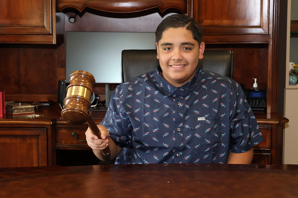 Honorary Mayor for the Day, Aaron Diaz, holds gavel and smiles for a photo.